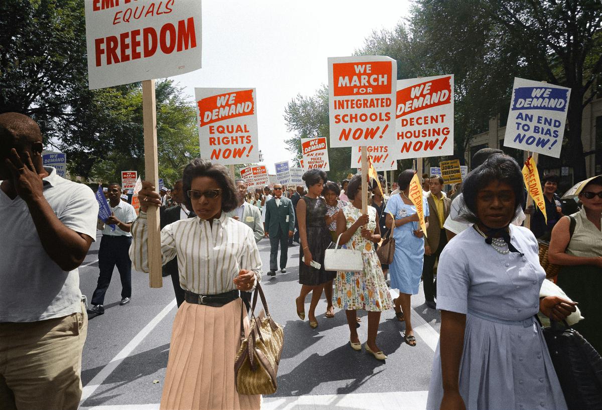 Young diverse protesters at a modern civil rights rally holding signs inspired by MLK's dream